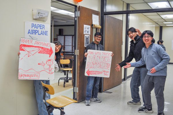 Volunteers welcome parents and children to he paper airplane-making station!